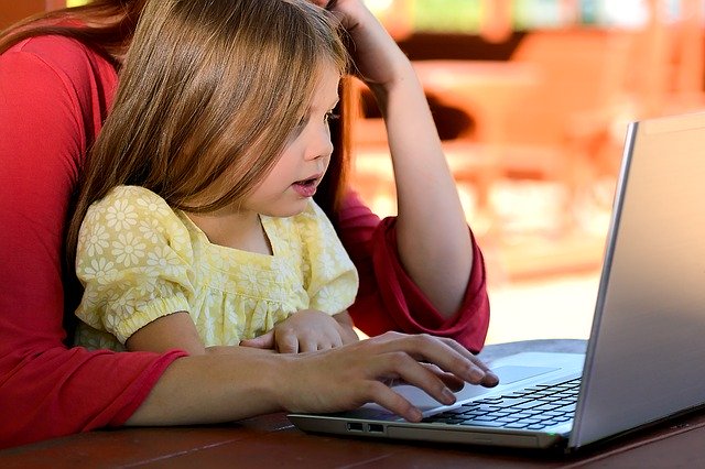 Child on mother's lap while she works at computer