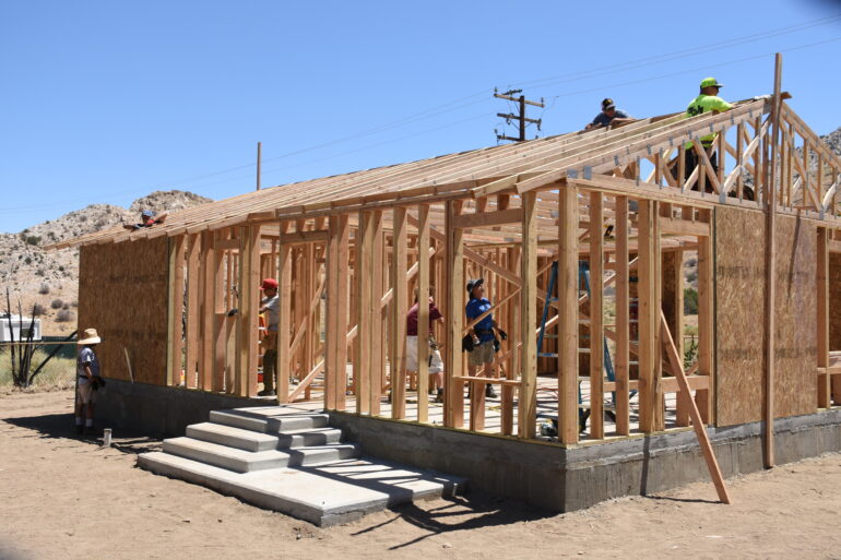 some people standing inside of a partially built out wooden frame of a house
