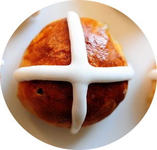 a top down image of a bun with a white icing cross on top