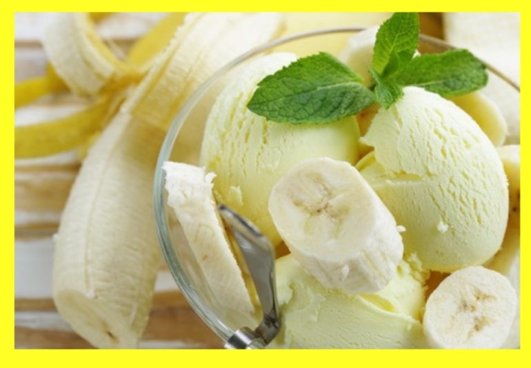 Ice cream topped off with sliced banana and decorated with mint leaves and a banana half-peeled next to the bowl