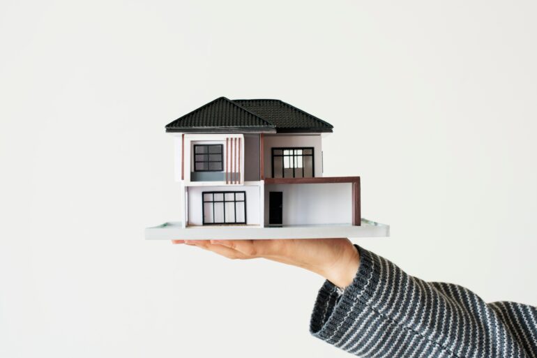 a house model in a hand. Accredited:<a href="https://www.freepik.com/free-photo/hand-presenting-model-house-home-loan-campaign_15667726.htm#query=home&position=2&from_view=search&track=sph">Image by rawpixel.com</a> on Freepik