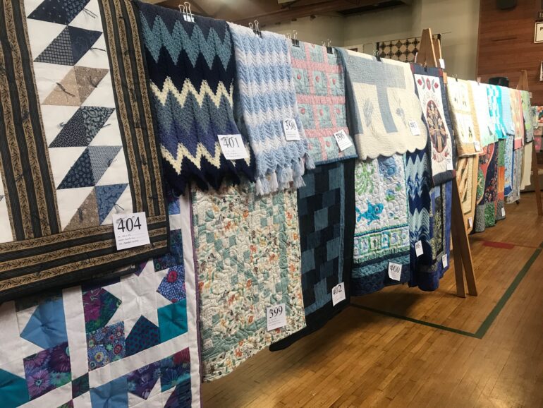 A row of hung up quilts.
