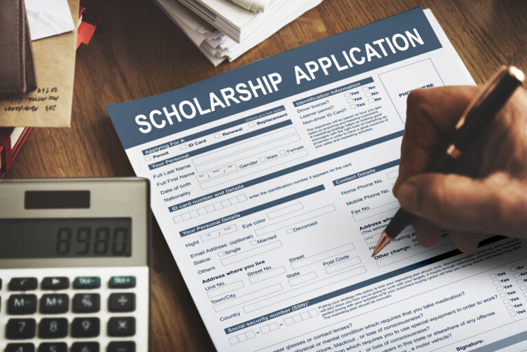 A person filling out a Scholarship Application.