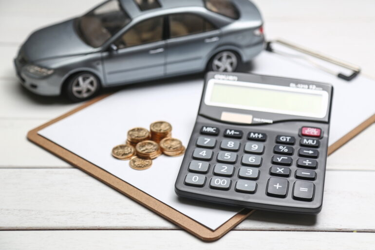 A model car sitting on top of a form in a clip board. On top of the form is a few small stacks of coins and a calculator. Picture from: <a href="https://www.freepik.com/free-photo/car-model-calculator-coins-white-table_1192516.htm#query=car%20insurance&position=8&from_view=search&track=robertav1_2_sidr">Image by xb100</a> on Freepik